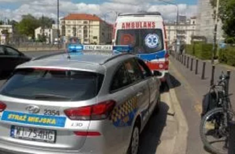 Samochód policyjny na miejscu wypadku z karetką i rowerem