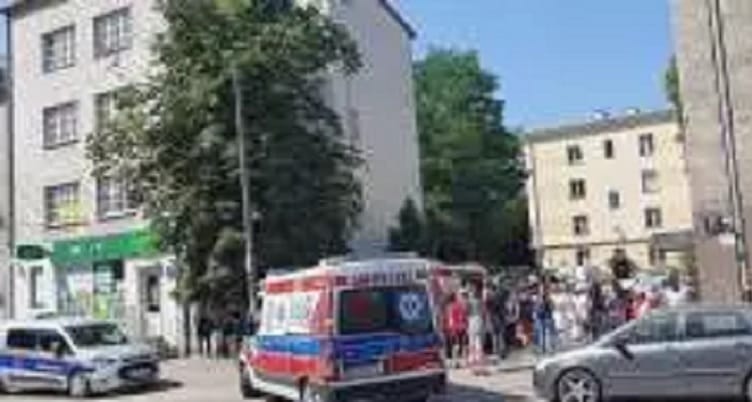 Ratownicy i tłum na miejscu zdarzenia w pobliżu budynku.