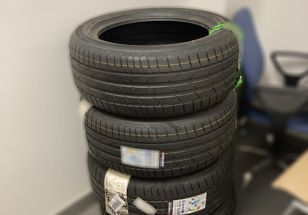 Stos trzech nowych opon samochodowych gotowych do montażu.