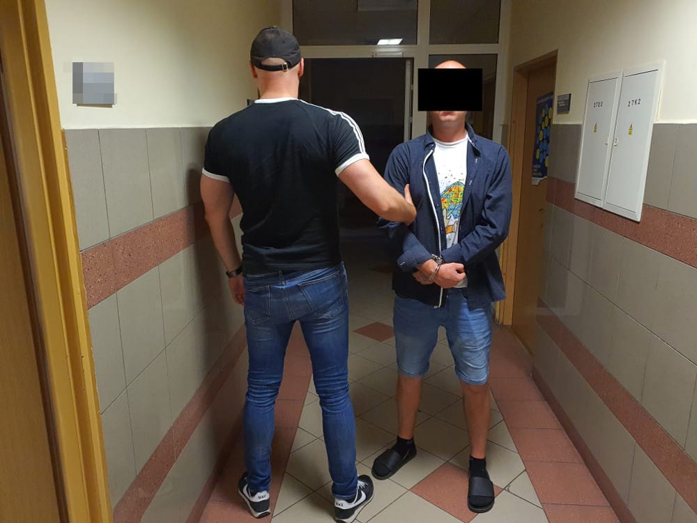 Policjant aresztujący podejrzanego na korytarzu