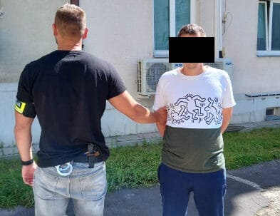 Policjant aresztujący podejrzanego z rękami skutymi z tyłu.