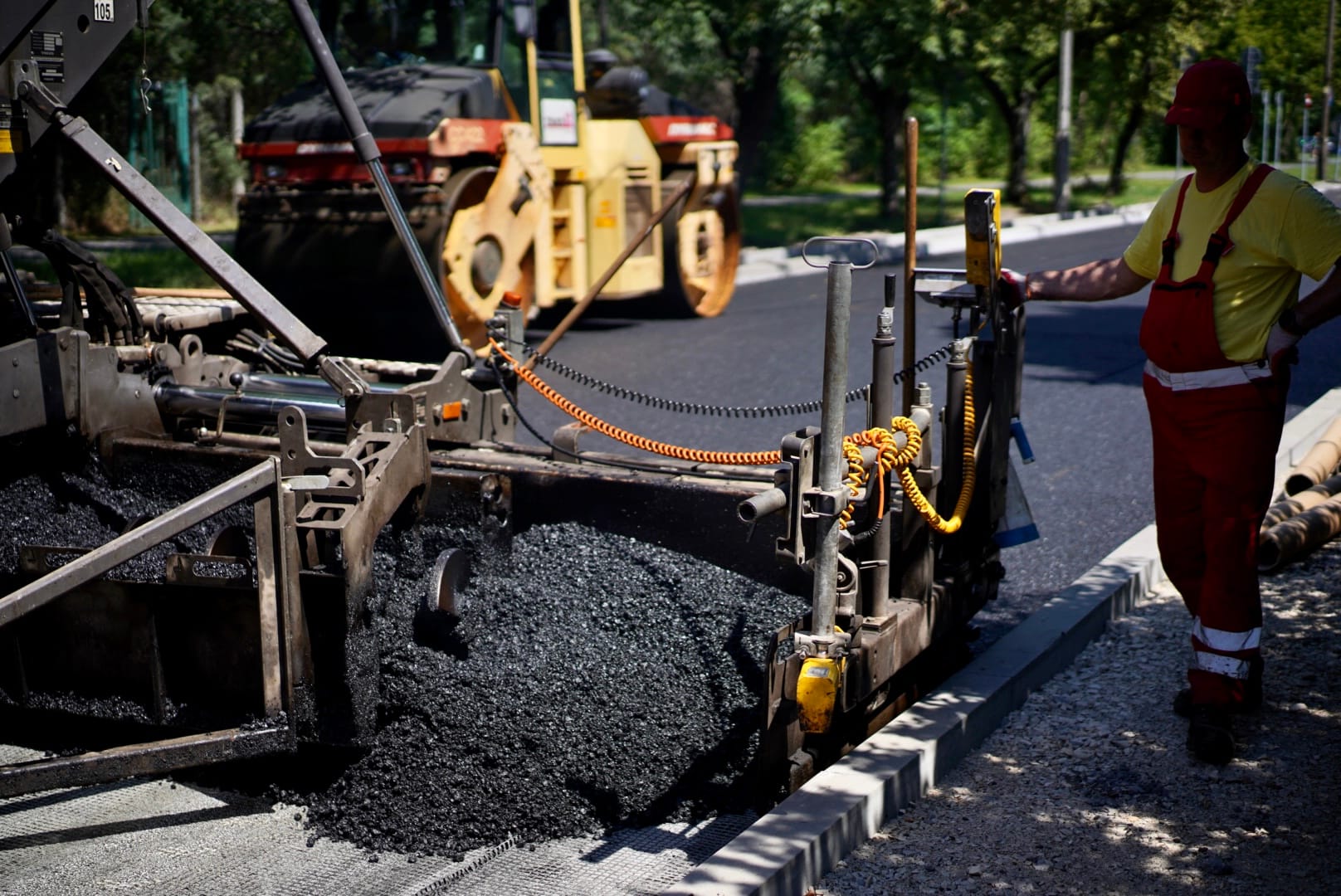 Ekipa drogowa układająca asfalt maszyną do układania nawierzchni
