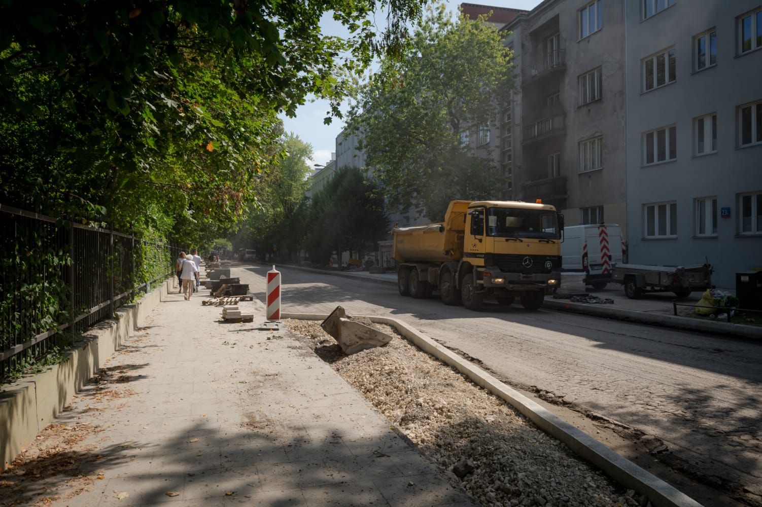 Ekipa budowlana pracuje na ulicy miejskiej, naprawiając chodnik i jezdnię.
