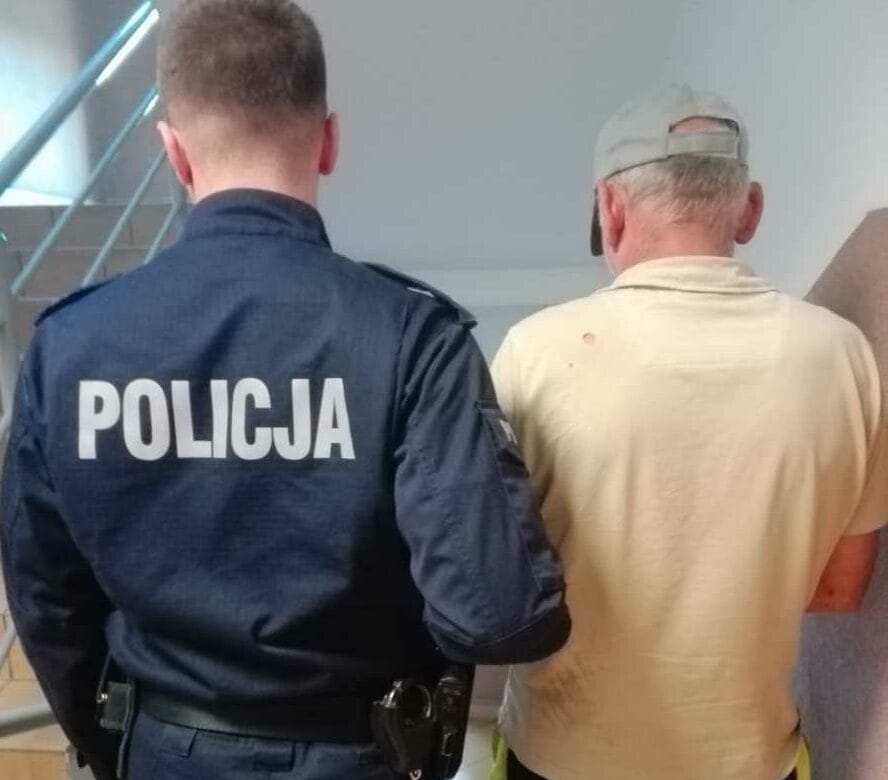Policjant aresztujący mężczyznę; na mundurze policjanta widoczny napis „Policja”.