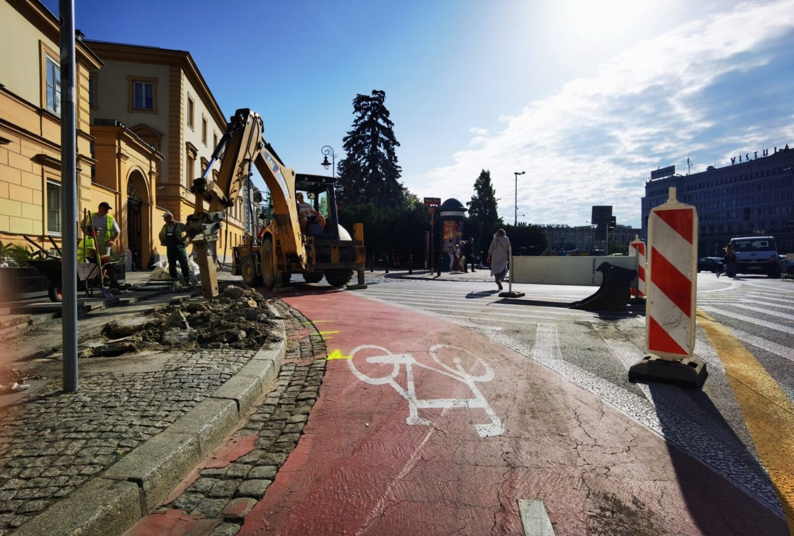 Ekipa drogowa używa koparki do naprawy miejskiej ścieżki rowerowej
