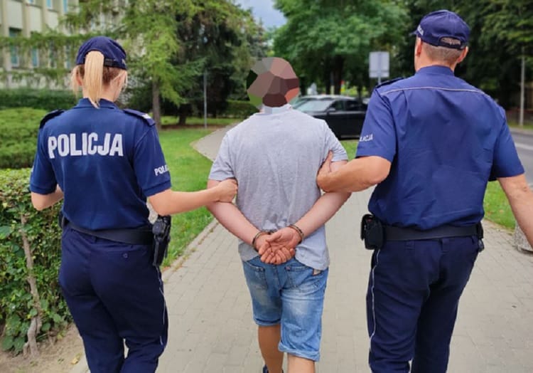Dwóch polskich policjantów eskortuje podejrzanego w kajdankach. POLICJA.