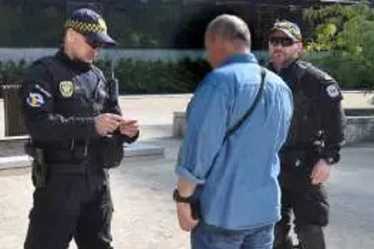 Dwóch policjantów rozmawia z mężczyzną na ulicy miasta.