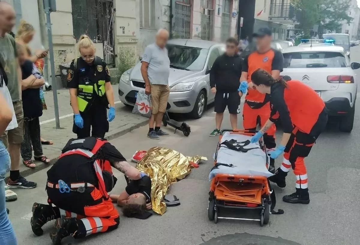 Ratownicy medyczni udzielają pomocy pacjentowi leżącemu na ziemi po wypadku.
