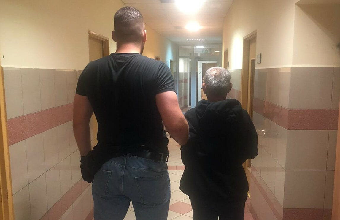 Mężczyzna eskortujący starszego mężczyznę korytarzem