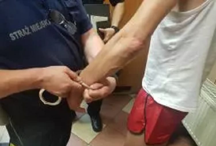 Policjant zakładający podejrzanemu kajdanki.