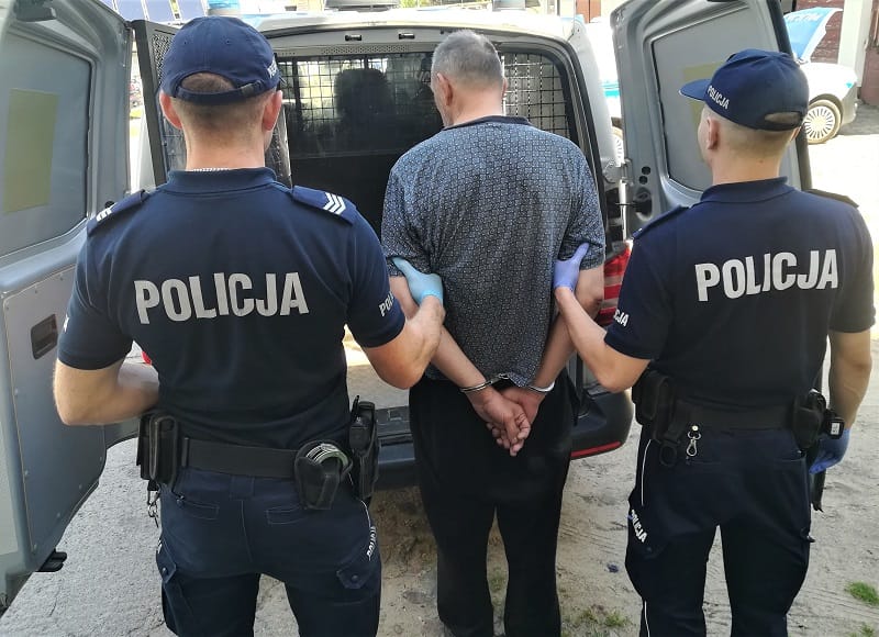 Dwóch polskich policjantów aresztuje zakutego w kajdanki mężczyznę. POLICJA