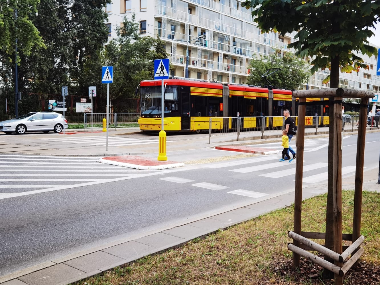 Rodzina przechodząca przez ulicę w pobliżu żółtego tramwaju, przejścia dla pieszych