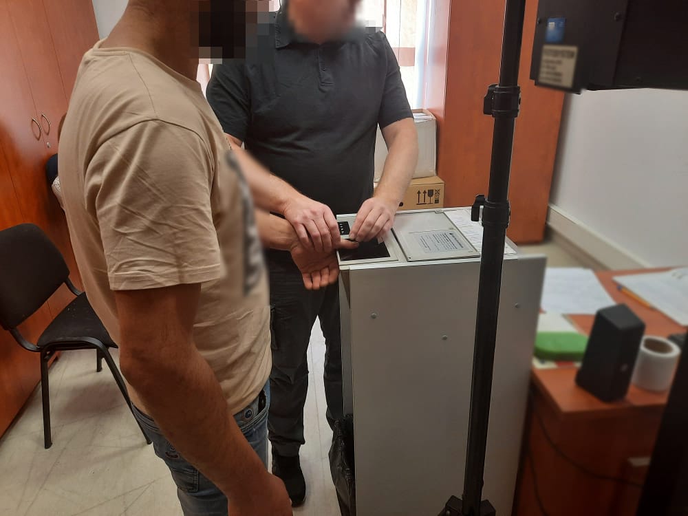 Policjant pobierający odciski palców od podejrzanego na posterunku policji