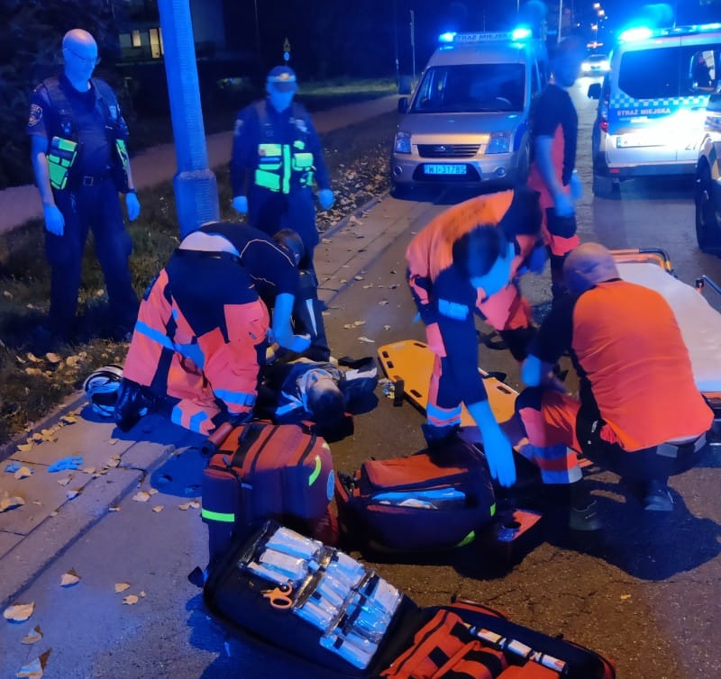 Ratownicy udzielają pomocy ofierze wypadku na miejskiej ulicy nocą.