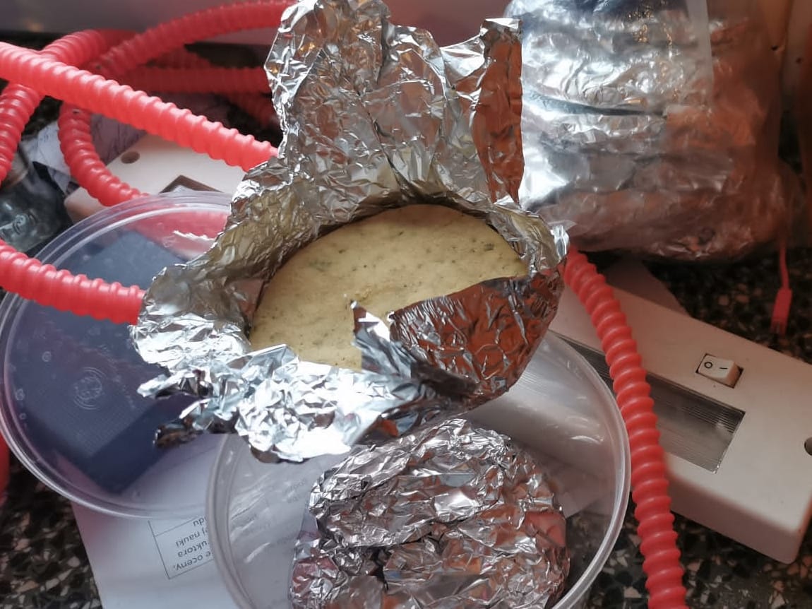 Pieczony ziemniak zawinięty w folię, obok innego jedzenia zawiniętego w folię.