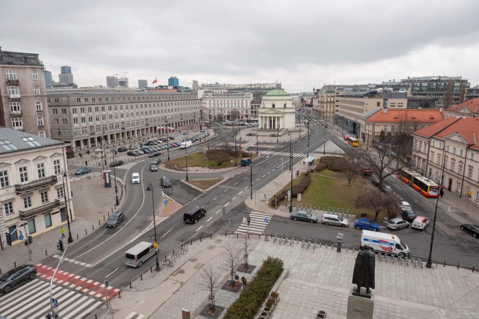Widok z lotu ptaka na centrum Warszawy, ukazujący ulice, budynki i rondo.