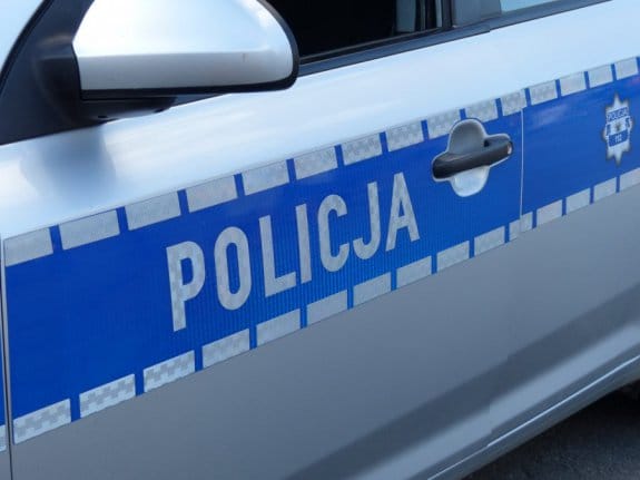 Zbliżenie na drzwi polskiego radiowozu, na którym wyraźnie widoczny jest napis „POLICJA”.