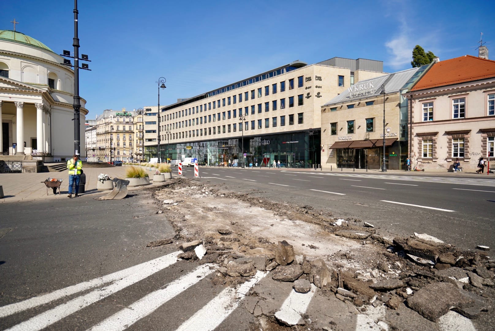 Ulica w Warszawie w trakcie budowy. Na zdjęciu widoczna zniszczona nawierzchnia i nowoczesne budynki.