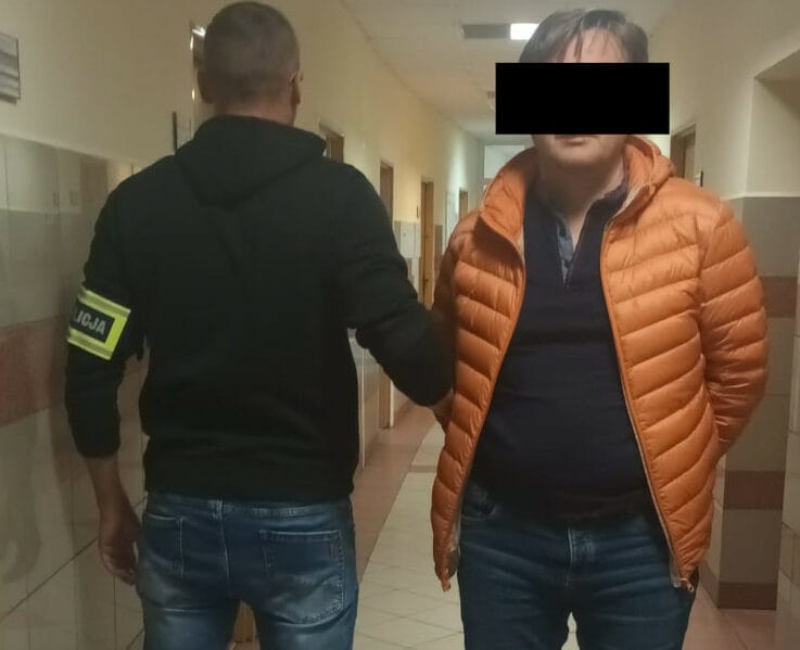 Policjant aresztujący podejrzanego na korytarzu