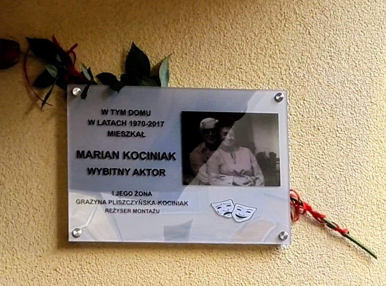 Tablica pamiątkowa poświęcona polskiemu aktorowi Marianowi Kociniakowi, 1970-2017, ze zdjęciem i maskami teatralnymi.