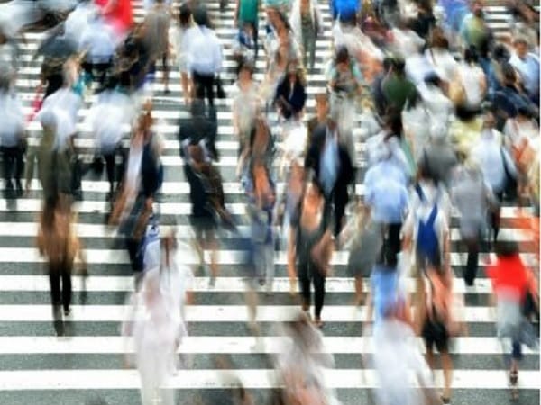 Rozmazany tłum ludzi przechodzących przez przejście dla pieszych.