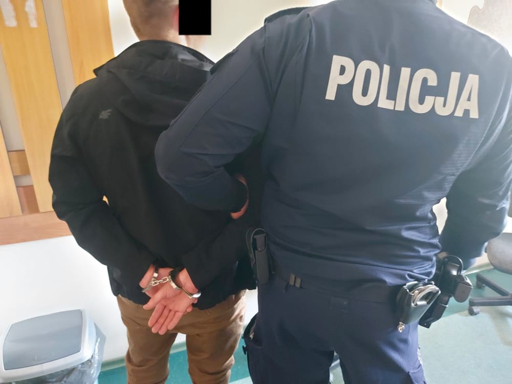Policjant aresztujący podejrzanego, widoczne kajdanki. POLICJA.