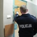 Policjant otwierający drzwi celi więziennej.