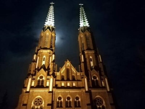 Nocny widok na oświetlone bliźniacze wieże Kościoła Mariackiego.