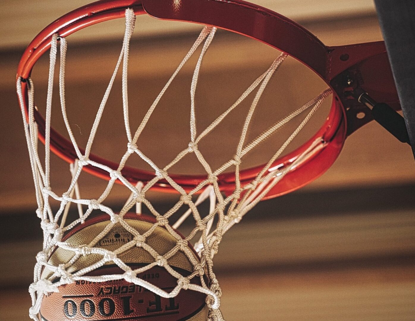 Piłka koszykarska przelatuje przez bramkę, widok z bliska na piłkę FT-1000 Legacy Deep.