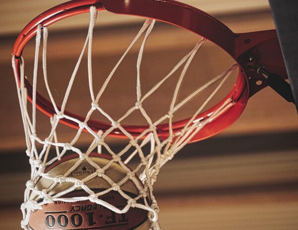 Piłka koszykarska przelatuje przez bramkę, widok z bliska na piłkę FT-1000 Legacy Deep.