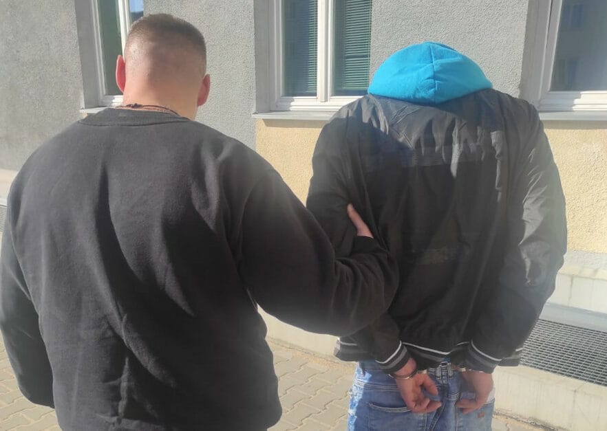 Policjant aresztujący podejrzanego z kajdankami.