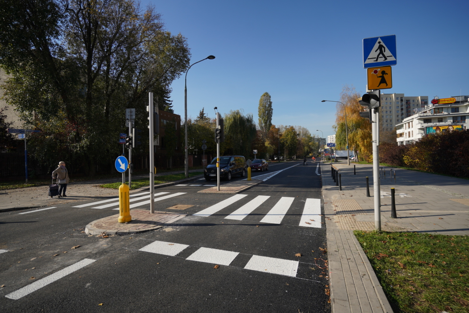 Przejście dla pieszych z sygnalizacją świetlną i oznakowaniem. Nowo wyasfaltowana droga.