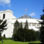 Budynek Sejmu w Warszawie, z powiewającą polską flagą.
