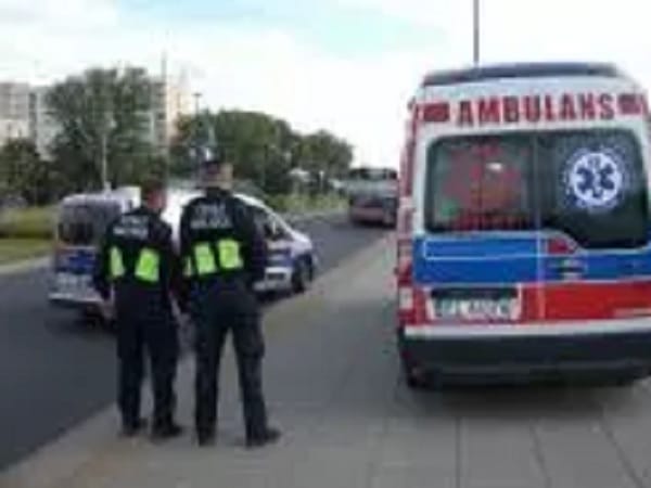 Dwóch policjantów stoi obok karetki pogotowia i wypadku samochodowego.