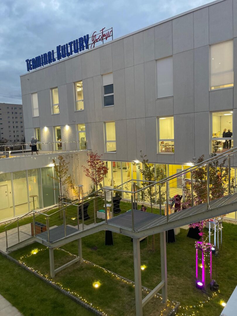 Widok zewnętrzny Terminalu Kultury Gocław, ukazujący nowoczesną architekturę i zagospodarowany dziedziniec z oświetleniem zewnętrznym.