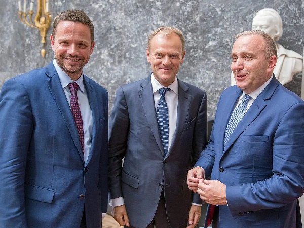 Trzech mężczyzn w garniturach, prawdopodobnie politycy, stoi razem do zdjęcia.