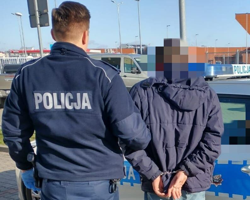 Policjant aresztujący podejrzanego, widoczne kajdanki. POLICJA