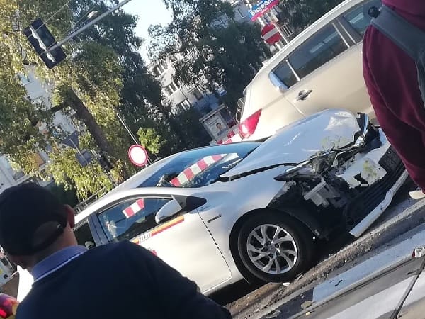Uszkodzona biała taksówka po wypadku samochodowym. Zderzenie czołowe.