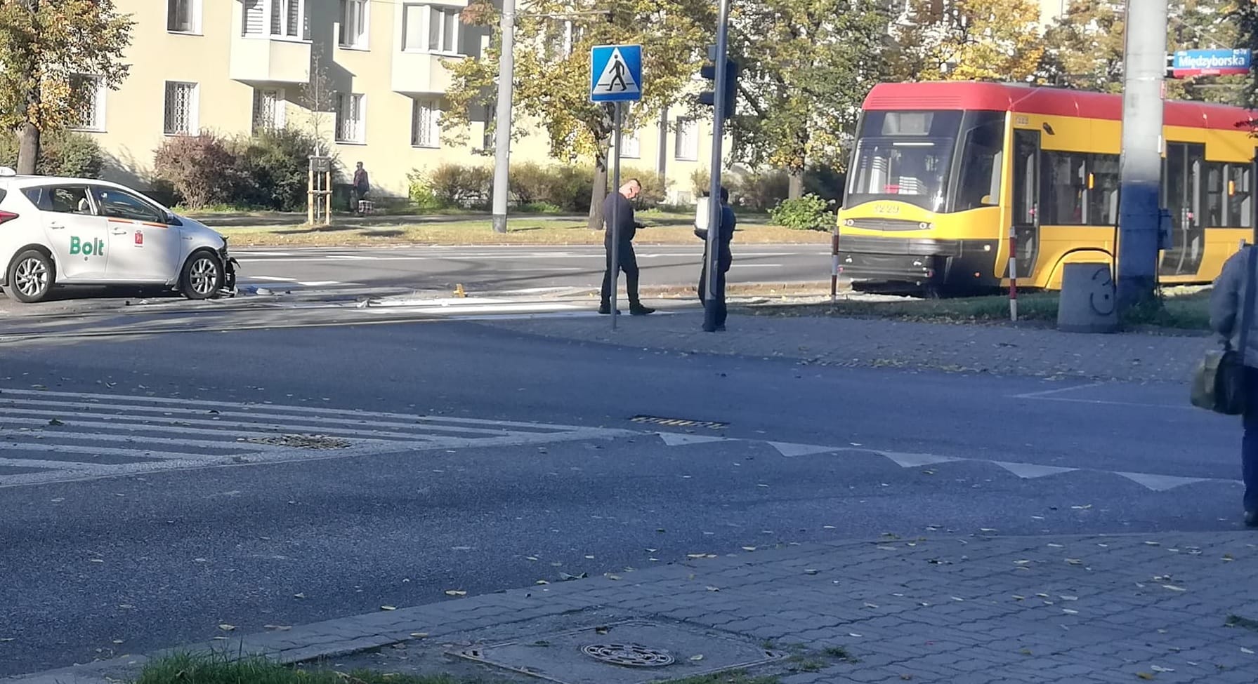 Uszkodzona taksówka Bolt po zderzeniu w pobliżu tramwaju, widać przejście dla pieszych