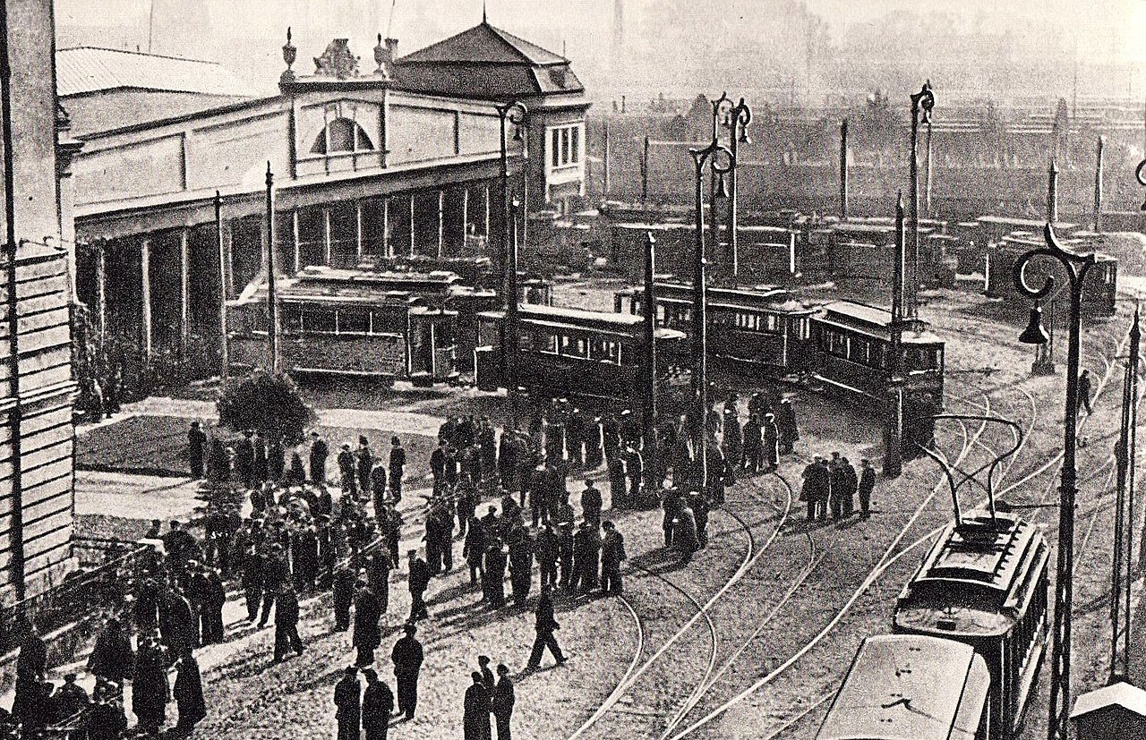 Zabytkowe tramwaje na ruchliwej stacji w Helsinkach, około początku XX wieku. Obecnych jest wiele osób.