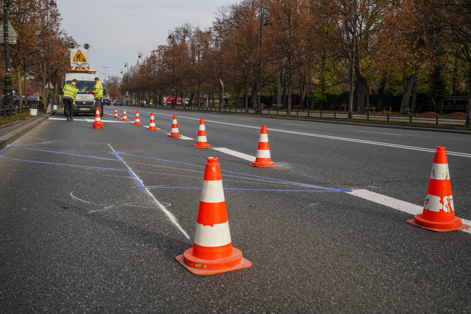 Robotnicy drogowi malują oznakowanie dróg pachołkami drogowymi