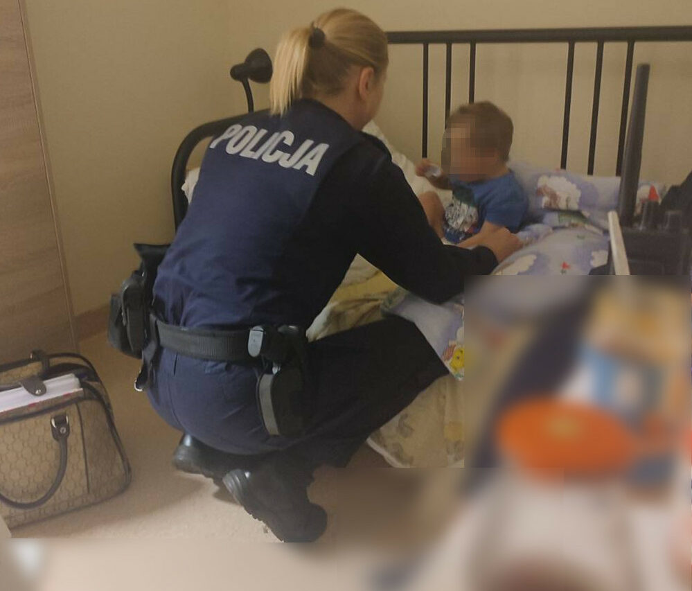 Policjant pocieszający dziecko w łóżku. POLICJA