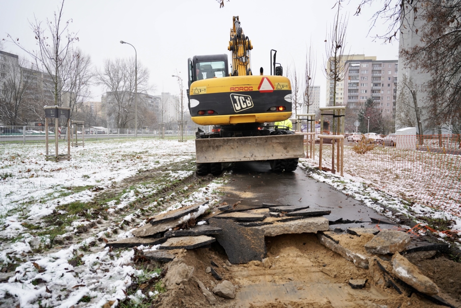 Koparka naprawiająca zaśnieżony chodnik miejski. Roboty drogowe JCB.