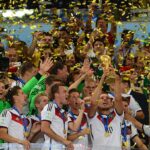 Reprezentacja Niemiec, która zdobyła Puchar Świata, świętuje zdobycie trofeum, a wokół rozpościerają się strumienie konfetti.