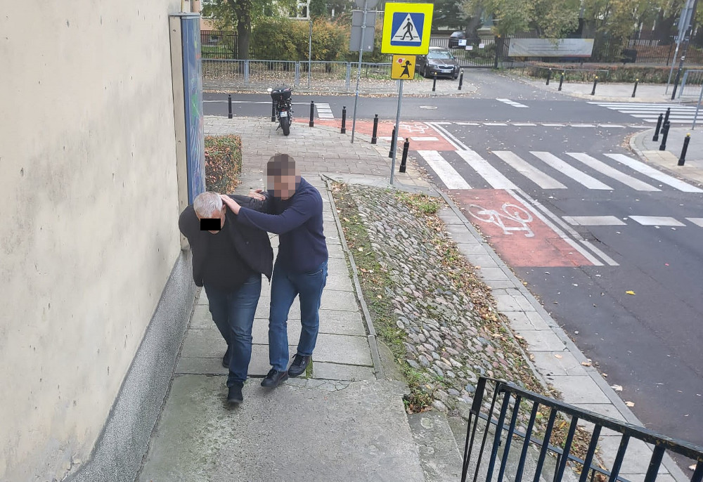 Mężczyzna pomagający starszej osobie zejść po schodach w pobliżu przejścia dla pieszych