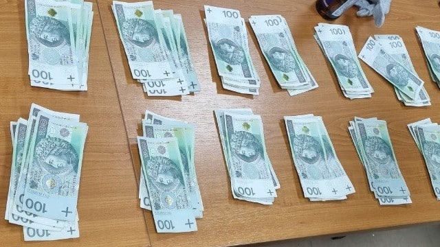 Stosy banknotów 100-złotowych ułożone na stole.