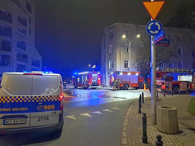 Pojazdy uprzywilejowane w nocy, wozy strażackie i radiowóz na skrzyżowaniu.