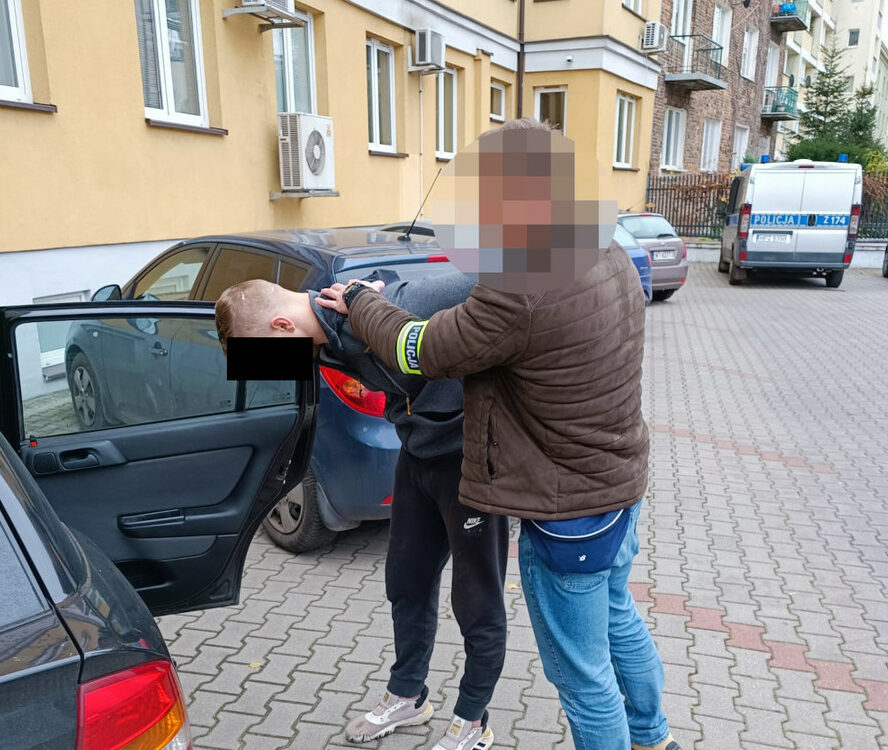 Policjant aresztujący podejrzanego, ręce z tyłu.