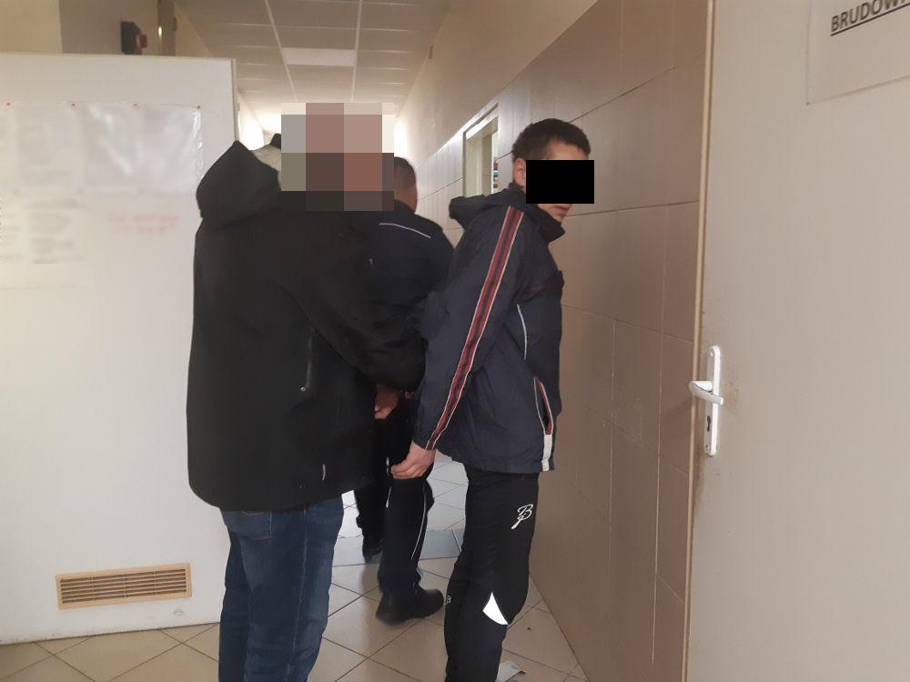 Policjanci aresztują młodego mężczyznę na korytarzu.