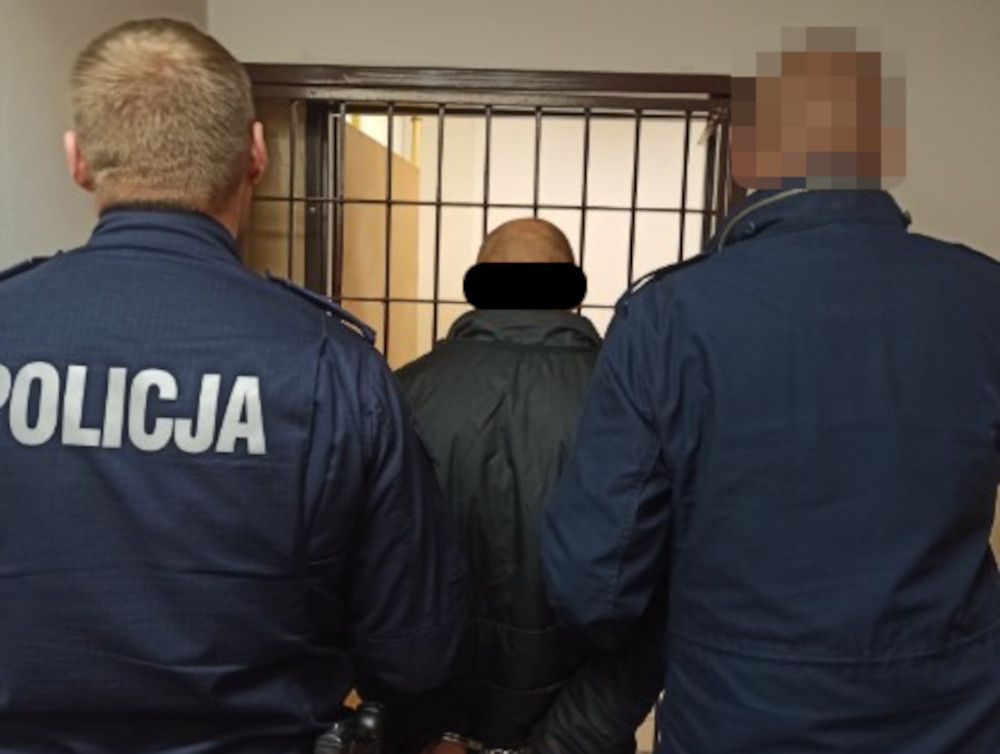 Policjanci eskortujący podejrzanego w kajdankach.